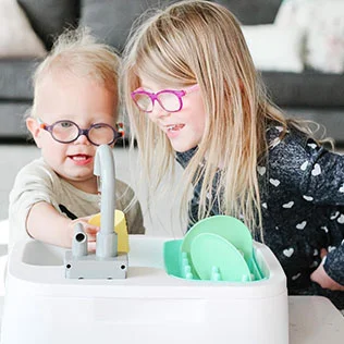 Siblings playing with the Super Sustainable Sink from The Helper Play Kit