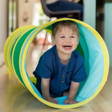 Child inside The Organic Cotton Play Tunnel by Lovevery