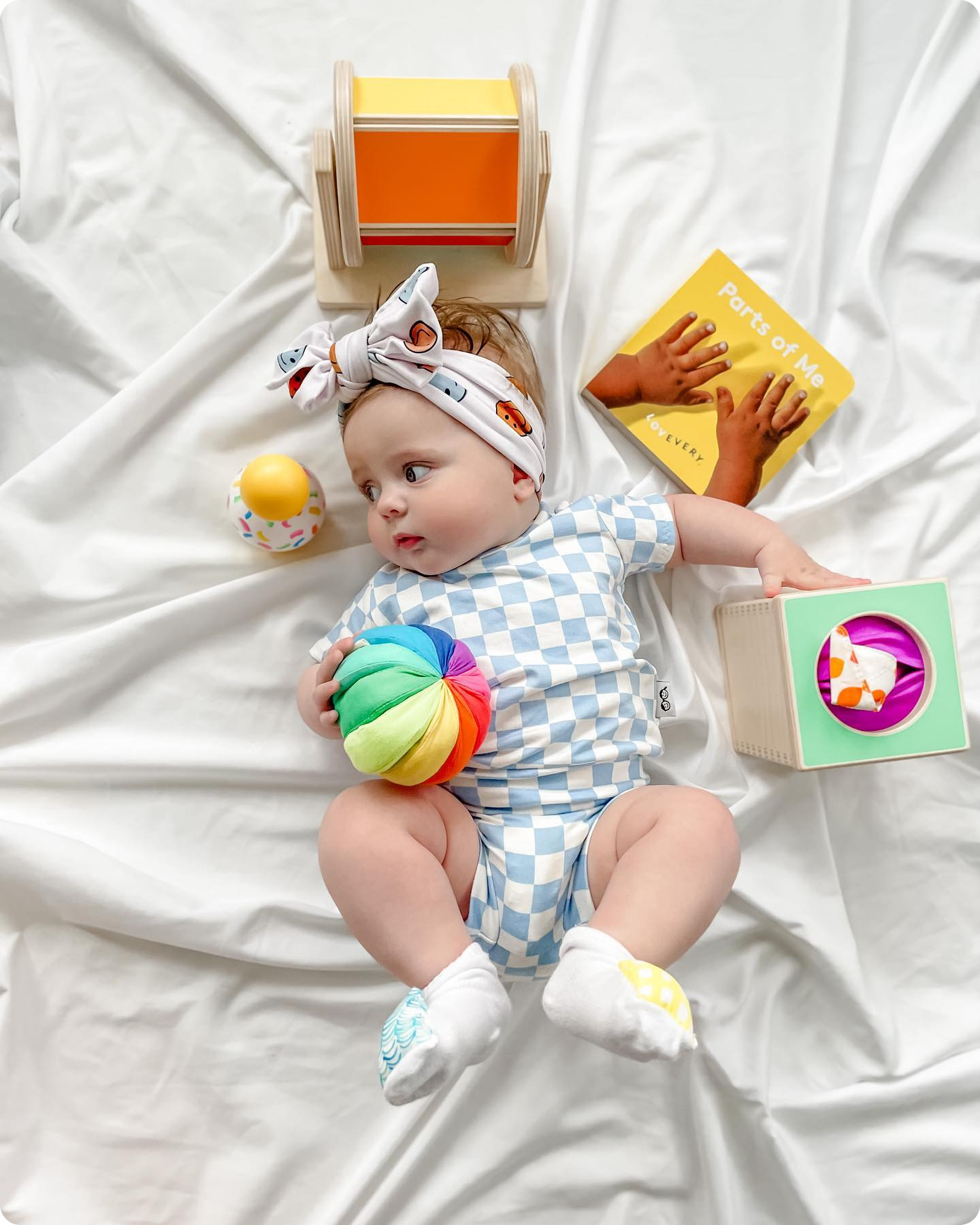 Baby laying with several playthings from The Senser Play Kit
