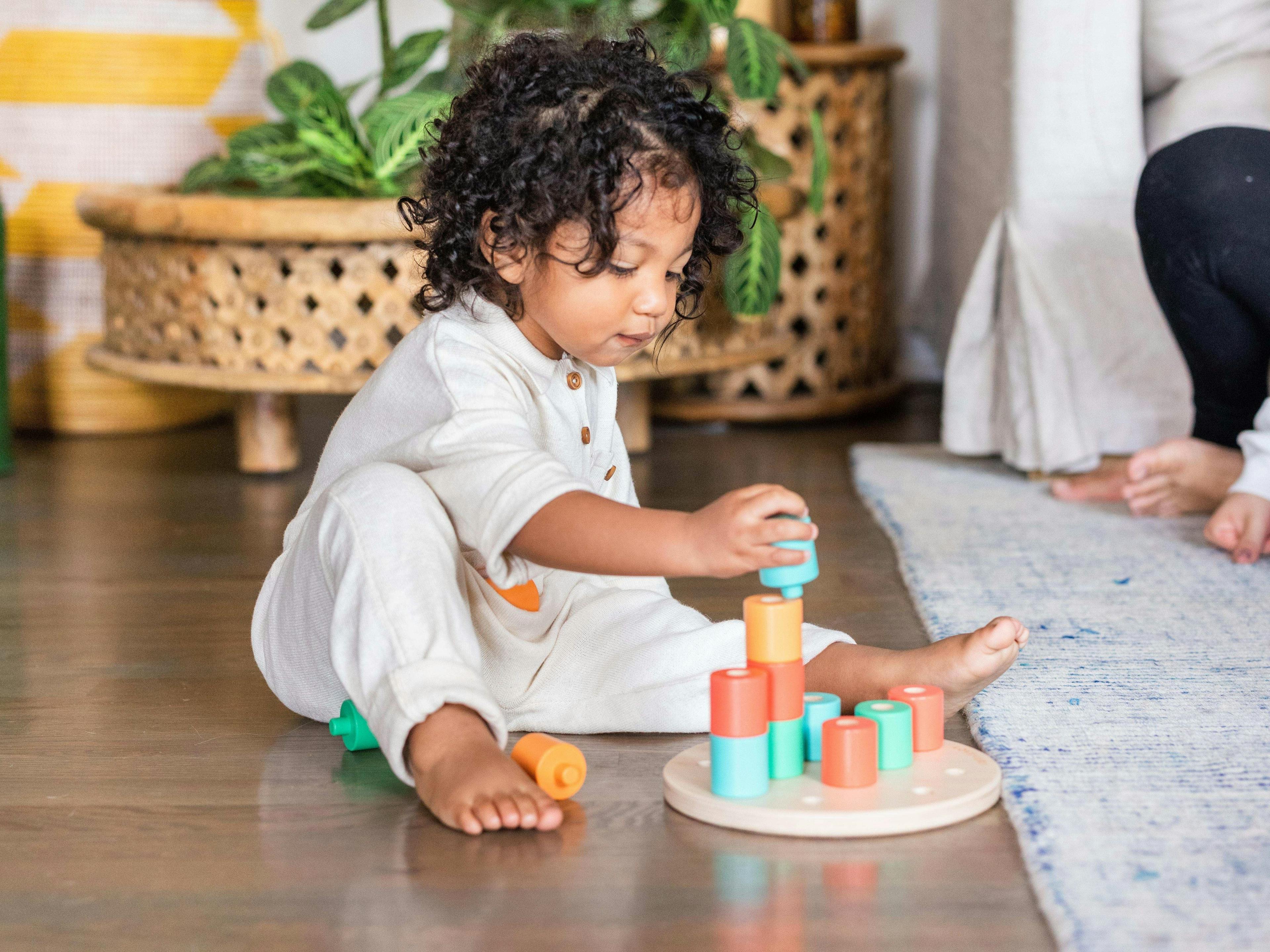 Child stacking rings on the Flexible Wooden Stacker from The Babbler Play Kit by Lovevery