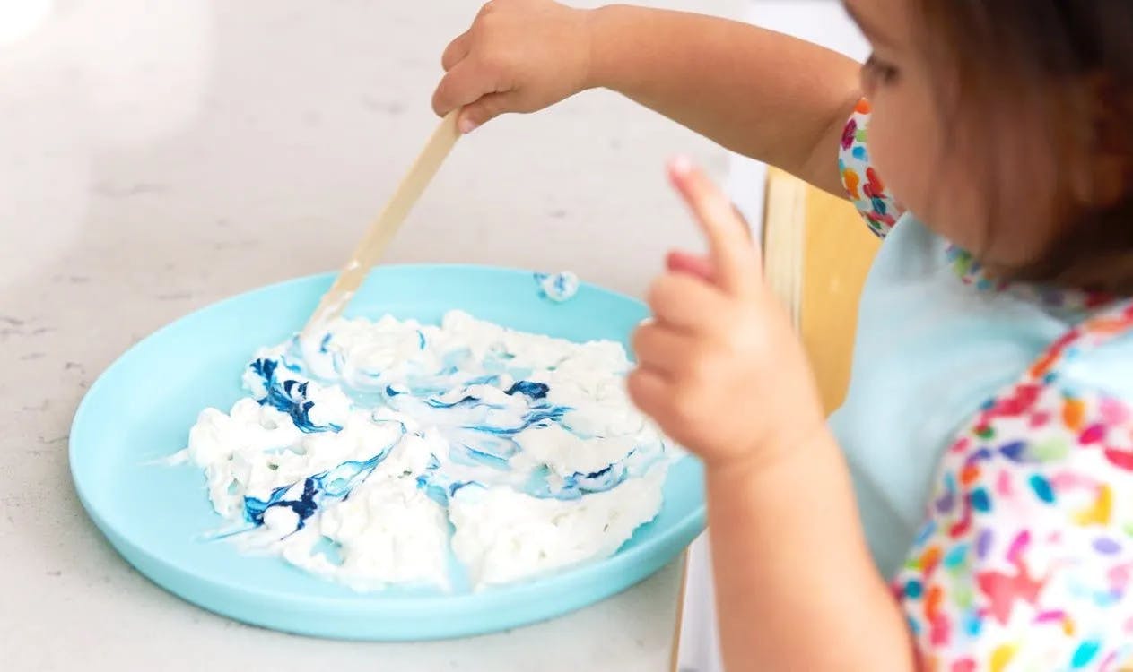 Child doing an art craft with shaving cream and paint