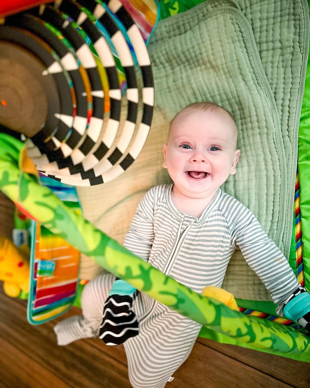 Happy baby looking up at The Mobile from The Looker Play Kit