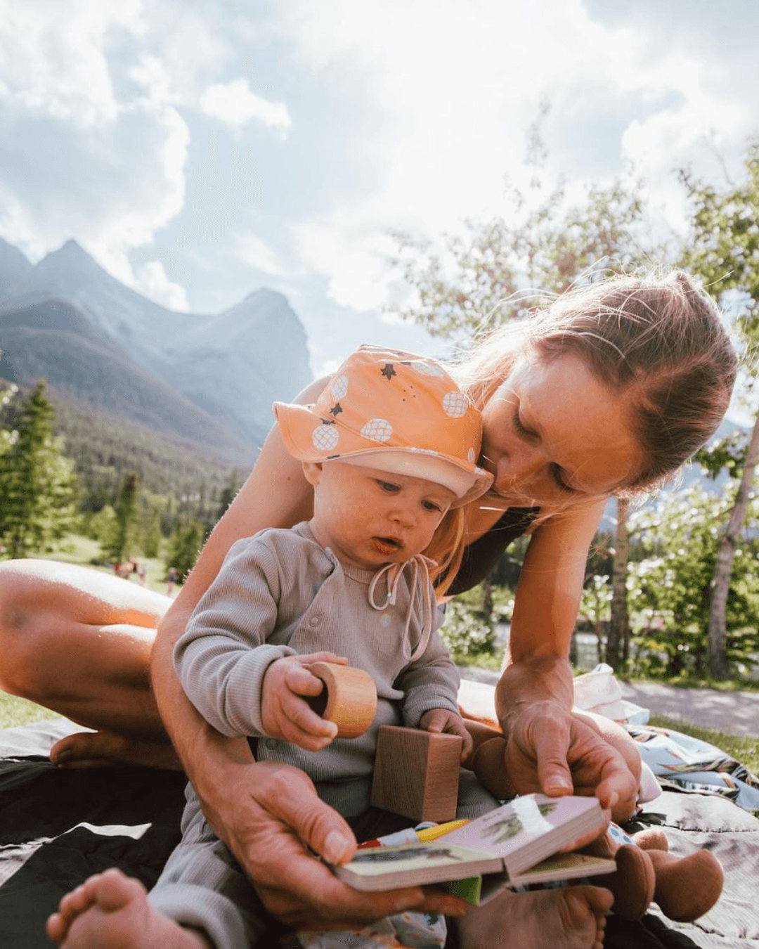 Child sitting on their mother's lap looking at a Lovevery book