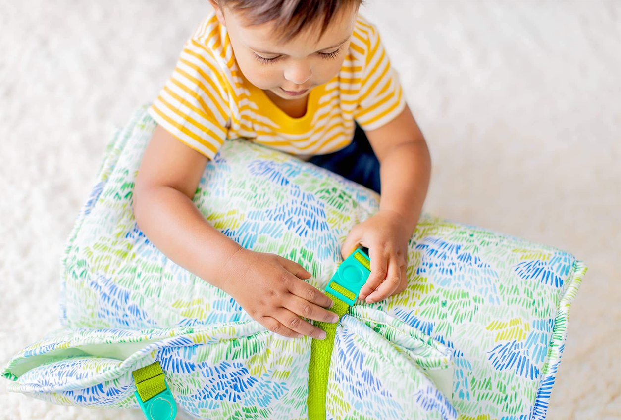 Child buckling the Nap Mat by Lovevery