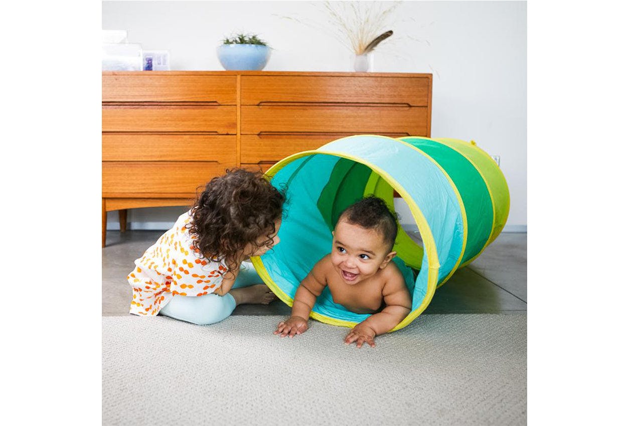 Two kids playing with The Cotton Play Tunnel by Lovevery